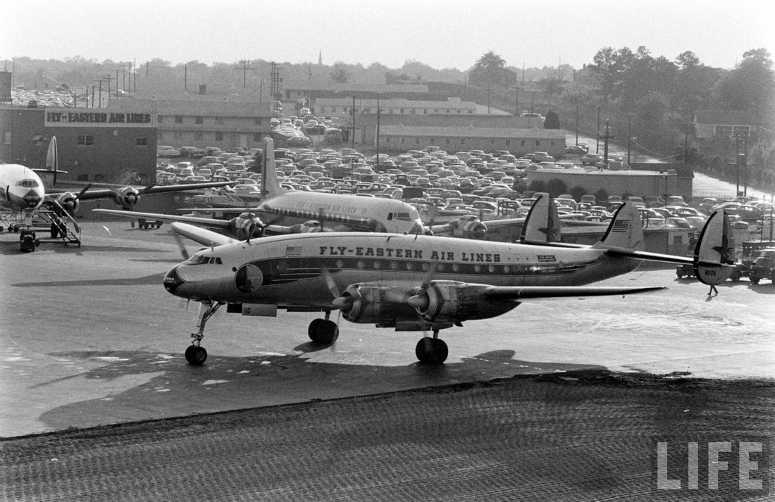 Eastern Air Lines N110A, a Lockheed L-749A Constellation, is followed by a DC-7 out to the active runway. This view faces west with the town of College Park in the distance.